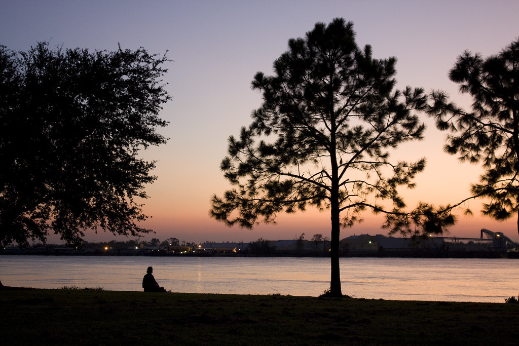Silhouette of a person sitting by a lake at sunset